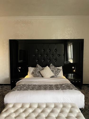 a bedroom with a large bed with a black headboard at The Castle Hotel in Amman
