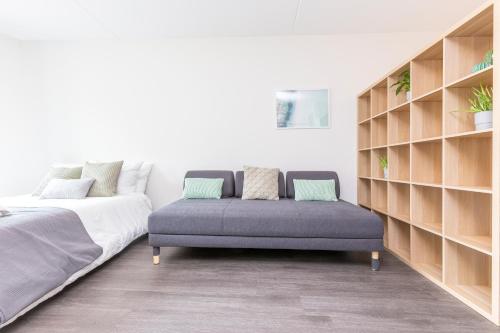 ein Schlafzimmer mit einem Bett, einem Sofa und Regalen in der Unterkunft Newly build Loft city center Delft XL Family apartment in Delft