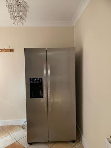 a stainless steel refrigerator in the corner of a room at Super King Bed Suite, Executive office, fast WiFi, free parking in St Ives