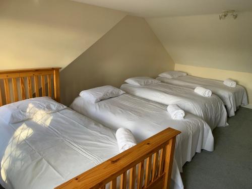 three beds in a room with white sheets and pillows at Super King Bed Suite, Executive office, fast WiFi, free parking in St Ives