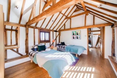 two beds in a room with wooden beams at Luxury, countryside barn conversion with Hot tub in Kent