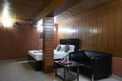 een kamer met een bed, een stoel en een tafel bij Hotel Quadis - Noida sec 15 in Noida