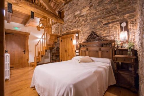 a bedroom with a large white bed in a stone wall at CASA DE ALDEA VAL DOS SOÑOS in Lugo