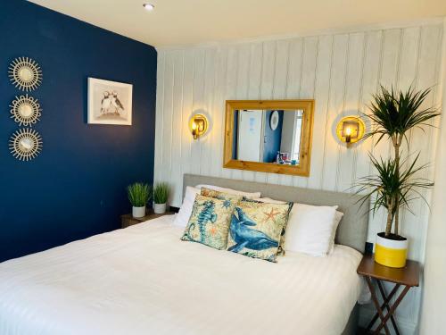 um quarto com uma cama branca e uma parede azul em Gazelle Hotel em Menai Bridge