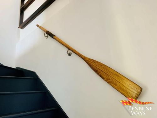 un murciélago de madera colgado en la pared junto a las escaleras en The Boat House, Northumberland Village Location, en Brampton