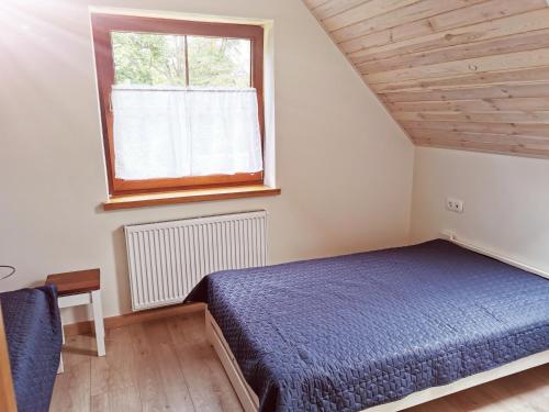 a bedroom with a blue bed and a window at Zwierzyniec u Kowala in Zwierzyniec