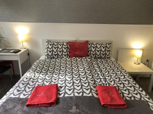 a bedroom with a large bed with two red pillows at Mandula Apartman in Cegléd