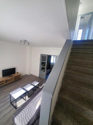 a living room with a staircase with a couch and a television at Maison au pied du château in Châteaudun