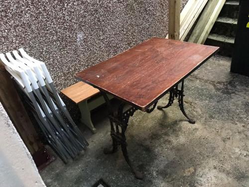 a wooden table and a chair sitting next to a bench at Coronation Place in Troed-y-rhiw