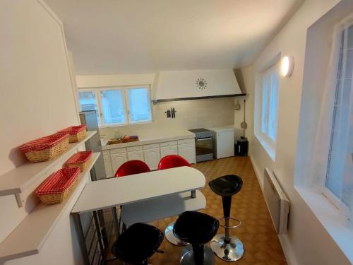 une cuisine avec des chaises rouges et un comptoir blanc dans l'établissement Pause entre deux Meaux ► Proche Disneyland Paris ► WiFi ► Netflix ► 24/24h, à Penchard