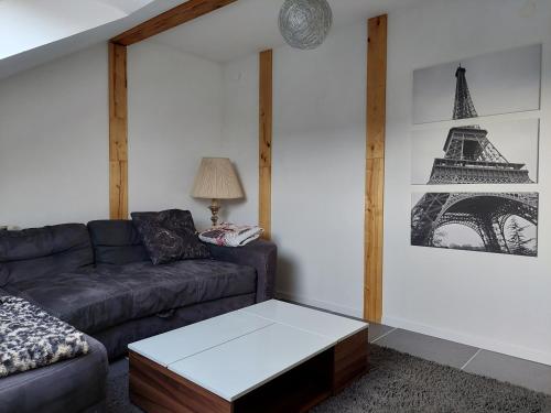 a living room with a couch and a picture of the eiffel tower at ALB-Wohnung - Schwäbische Alb in Heroldstatt