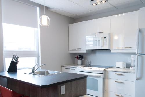 a kitchen with white cabinets and a black counter top at Le Chic-Urbain in Rouyn