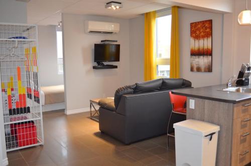 a living room with a couch and a kitchen at Le Chic-Urbain in Rouyn