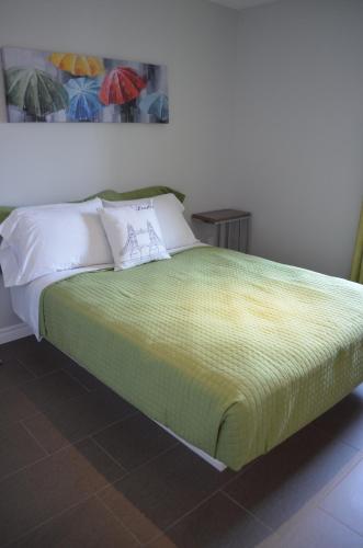 a bed with a green blanket and white pillows at Le Chic-Urbain in Rouyn