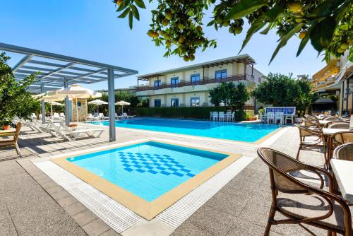 een zwembad met stoelen en een gebouw bij Ilyssion Holidays Hotel in Ialyssos