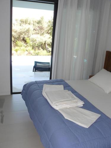 1 dormitorio con cama con sábanas azules y ventana en Villa Mytikas, luxury in Greece with seaview and heated pool & jacuzzi, en Pogoniá