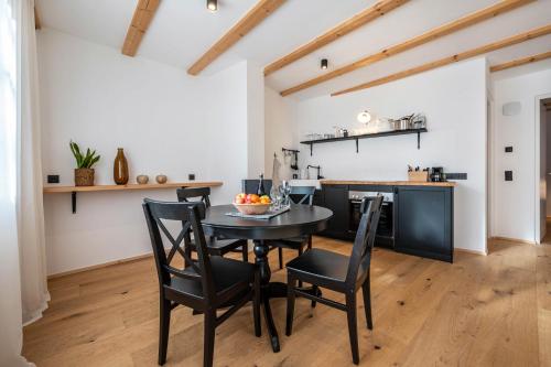 a kitchen and dining room with a black table and chairs at Binderhof Apt Obm in Brixen