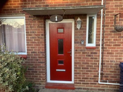a red door on the side of a brick house at St Ives, King Bed Cosy home, parking, fast Wi Fi in St Ives