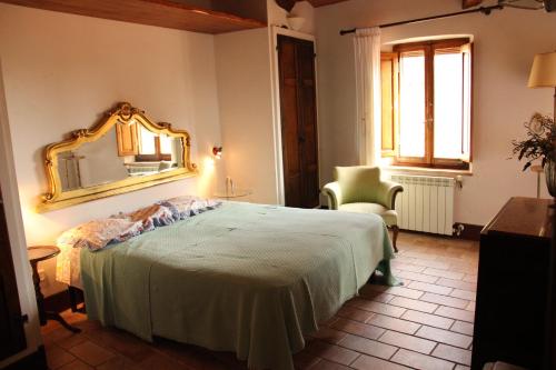 a bedroom with a bed and a mirror and a chair at Trilocale nel centro storico in Montemerano