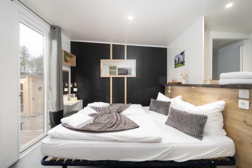 um quarto com uma cama com lençóis brancos e almofadas em Mobilheim am Murner See - private Sauna + privater Badezuber em Wackersdorf