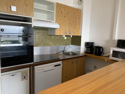 une cuisine avec un évier et une cuisinière four supérieur dans l'établissement Appartement T2 RDC avec Jardinet et Accès Direct Plage, Parking Sécurisé, Proche Commerces - FR-1-374-2, à Arcachon