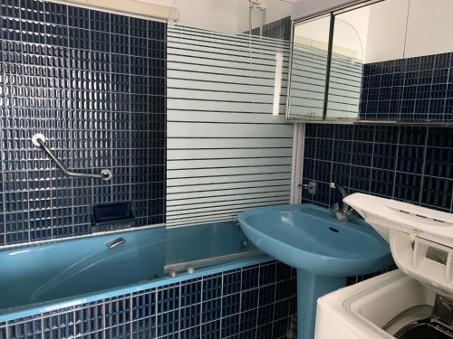 La salle de bains est pourvue d'un lavabo bleu et d'une baignoire. dans l'établissement Appartement T2 RDC avec Jardinet et Accès Direct Plage, Parking Sécurisé, Proche Commerces - FR-1-374-2, à Arcachon