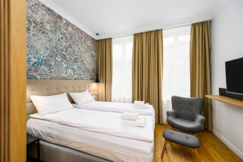 a hotel room with a bed and a chair at New Sobieski Apartments by OneApartments in Sopot
