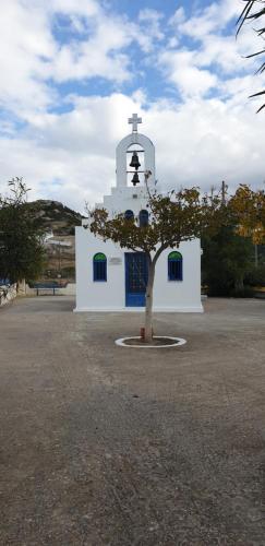 a small white church with a bell tower and a tree at Sea View Holiday House in Archangelos