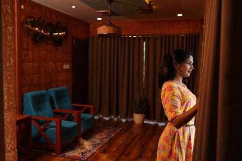 a woman in a dress standing in a room at Mount Stratus Resort Vayalada in Bālūssheri