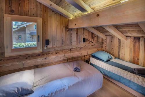 2 Betten in einem Blockhaus mit Fenster in der Unterkunft Chalet Pierre d Anatase in Saint-Gervais-les-Bains