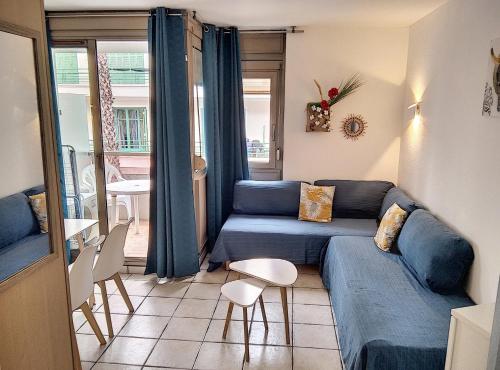 ein Wohnzimmer mit einem blauen Sofa und einem Tisch in der Unterkunft Résidence Graziella Studio 301 in Juan-les-Pins