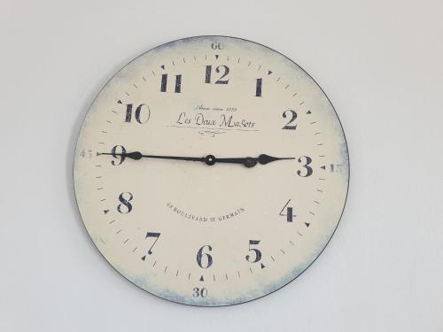 a clock is hanging on a white wall at Sea View Holiday House in Archangelos