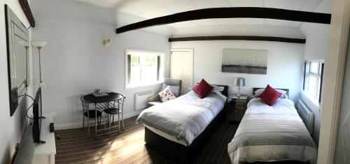 sypialnia z 2 łóżkami i czerwonymi poduszkami w obiekcie The Annex w mieście Malton