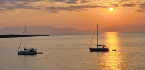 two boats sitting in the water at sunset at Sea View Holiday House in Archangelos