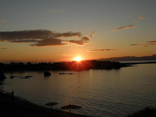 a sunset over a body of water with boats at Sea View Holiday House in Archangelos