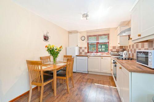 a kitchen with a table and chairs and a kitchen with white cabinets at OAK 2 Bedroom Lodge in Kingsnorth