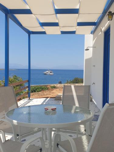 a patio with a table and chairs and the ocean at Sea View Holiday House in Archangelos