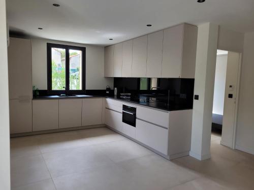 une cuisine avec des armoires blanches et des appareils noirs dans l'établissement Villas Clairette, à Gréasque