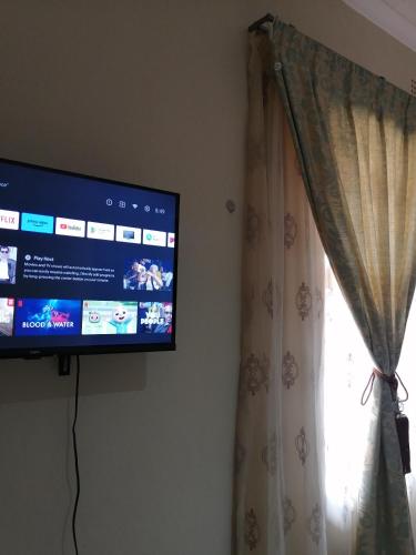 a flat screen tv hanging on a wall next to a window at Beautiful & Serene Airbnb house in Klerksdorp