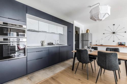 une cuisine avec des placards bleus et une table et des chaises en bois dans l'établissement Le Cour Bastille - avec terrasse en bail mobilité, à Nantes
