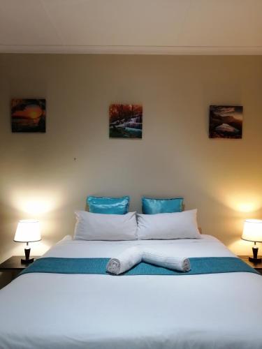 a bedroom with a large white bed with two lamps at Beautiful & Serene Airbnb house in Klerksdorp