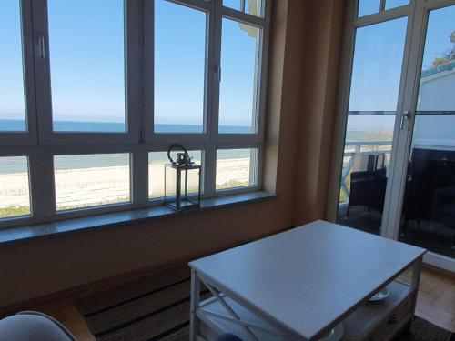 Zimmer mit einem Tisch und Fenstern mit Strandblick in der Unterkunft Maisonettewohnung Strandburg in Lubmin