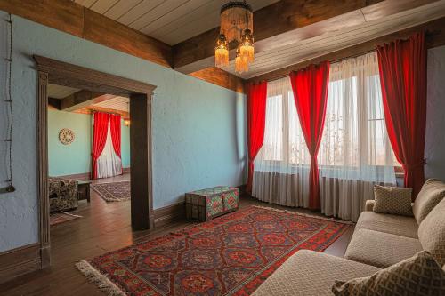 a living room with red curtains and a couch at Knyazli Family Suites & Rooms in Kiçik Qaramurad