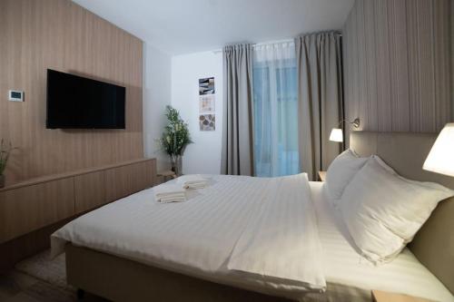 a bedroom with a large white bed with a flat screen tv at Carpe Diem Travel in Timişoara