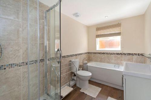 ein Bad mit einer Dusche, einem WC und einem Waschbecken in der Unterkunft ROSE - 2 Bedroom Cottage in Kingsnorth