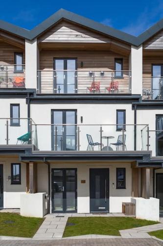 a large white building with chairs on the balcony at Luxury 3 floor Town House by Tolcarne Beach in Newquay