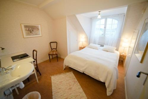 1 dormitorio con cama blanca y lavamanos en Liljeholmen Herrgård Hostel, en Rimforsa