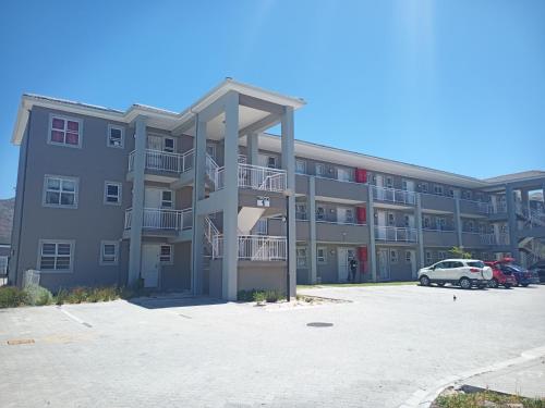 a large apartment building with a car parked in a parking lot at Dune Crest - 2 Bedroom Apartment in Cape Town