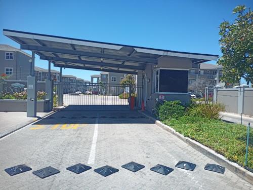 a parking lot with awning in front of a building at Dune Crest - 2 Bedroom Apartment in Cape Town
