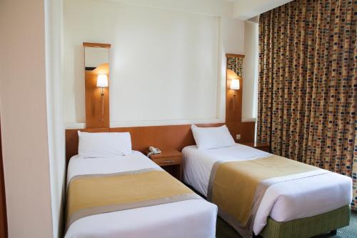 Pokój hotelowy z 2 łóżkami i lustrem w obiekcie Gorillas City Centre Hotel w mieście Kigali
